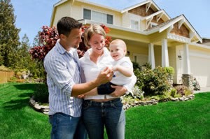 couple in front of new home with baby